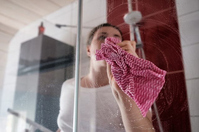Caucasian woman cleaning shower stall in the bathroom
