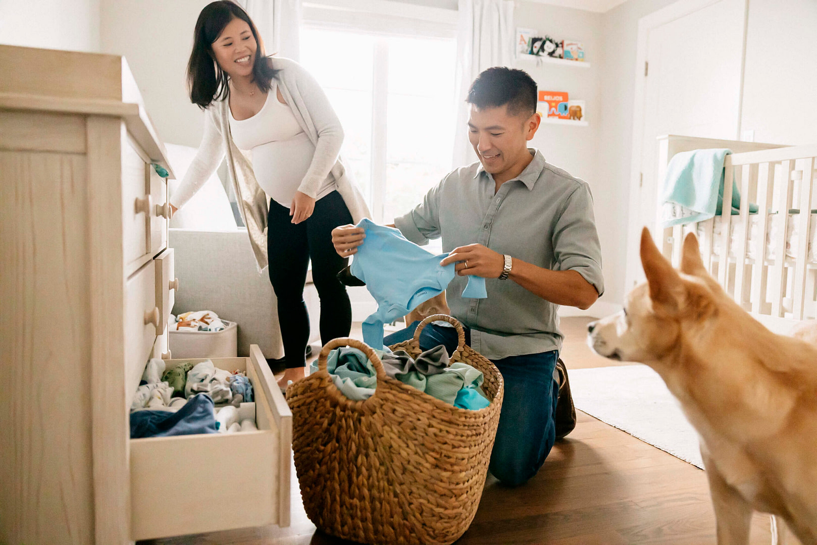pregnant mama and dad folding and putting away baby clothes in baby room